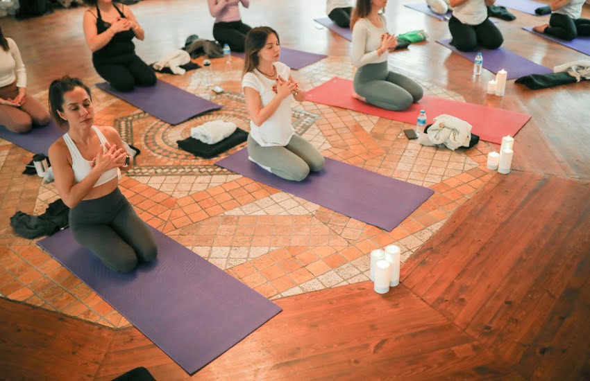 What is Yoga Teacher Training Really Like? Here's My Personal Experience 3 group of students sitting on yoga mats learning from a yoga teacher